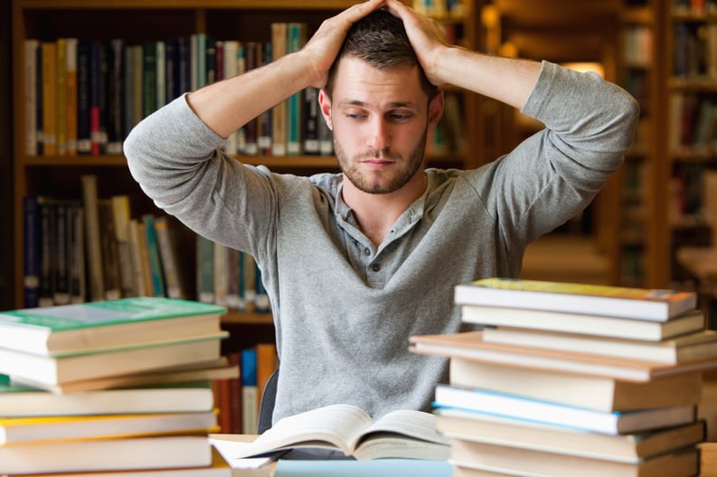 Tired student having too much to do in a library